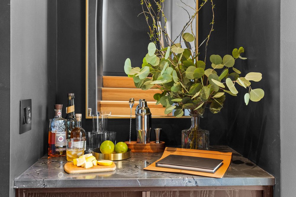 The bar: a dark cabinet with a mirror, cocktail shaker, glasses and fresh greenery