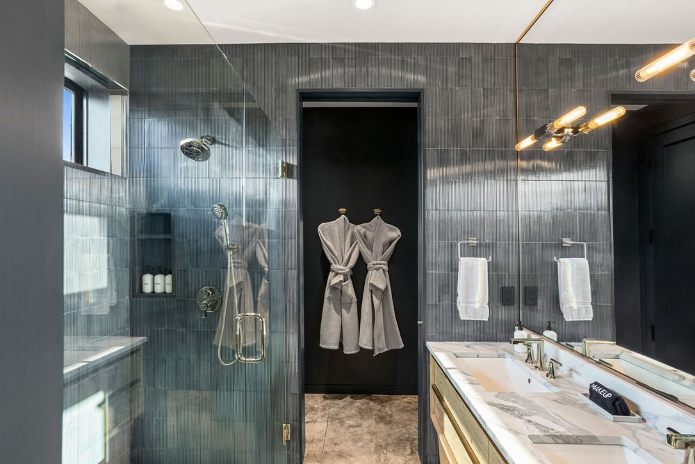 En-suite bathroom with a walk-in shower in rich blue fluted floor-to-ceiling tile and a marble double vanity