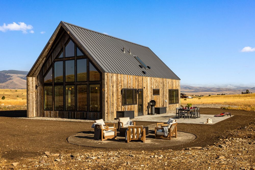 The glass gable end of the house with the patio and fire pit in the foreground