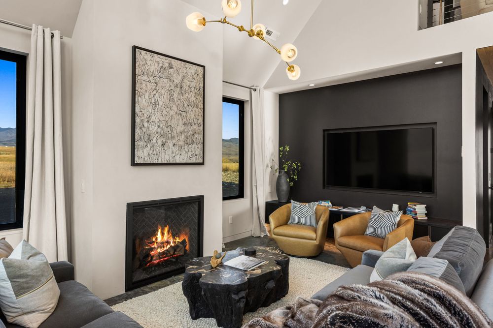 Gas fireplace with a fire lit, art above it, leather chairs and a sectional sofa