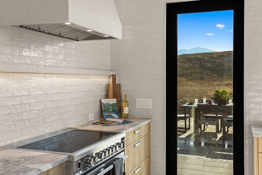 Range and hood against white hand-laid tile with light oak cabinetry