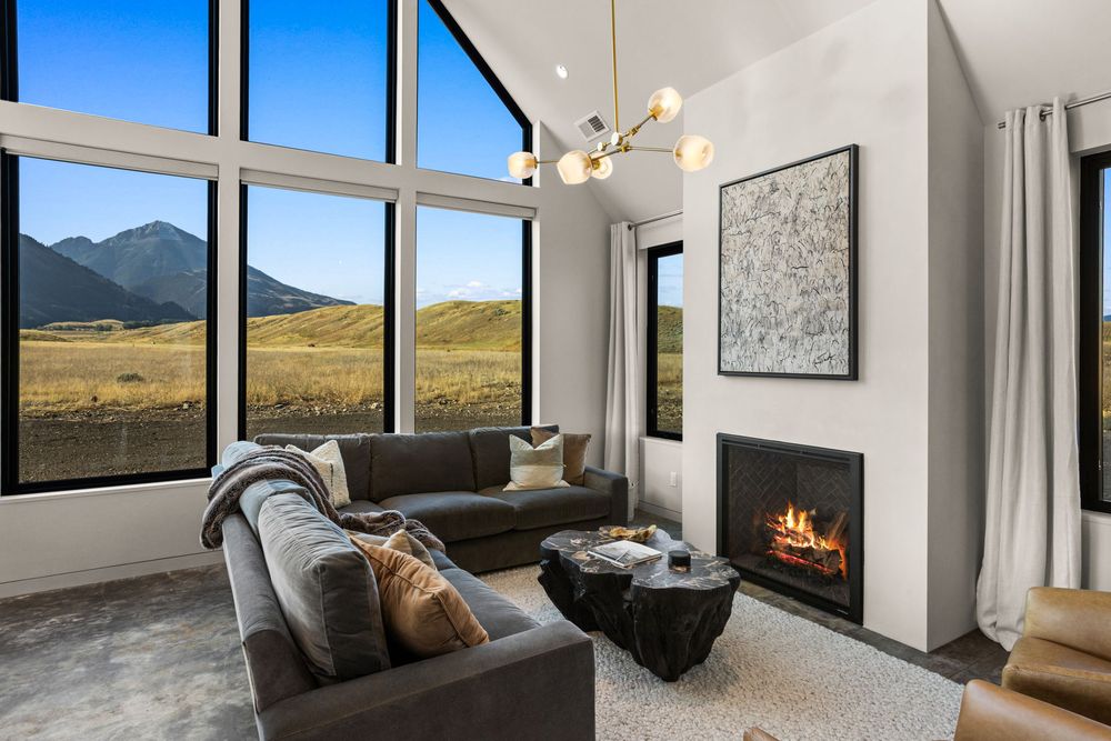 Living area with a gas fireplace, sectional sofa and valley views through tall windows