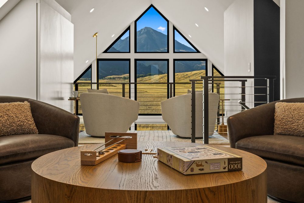 Loft sitting area with a game laid out on the round coffee table, gable window beyond