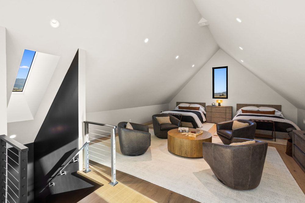 Wide view of the loft with swivel chairs, a round table and the stairs at the left under the vaulted ceiling