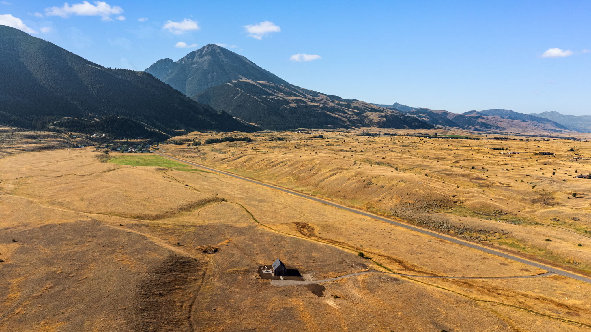 Glass House Montana — tiny in the Paradise Valley landscape with Emigrant Peak behind