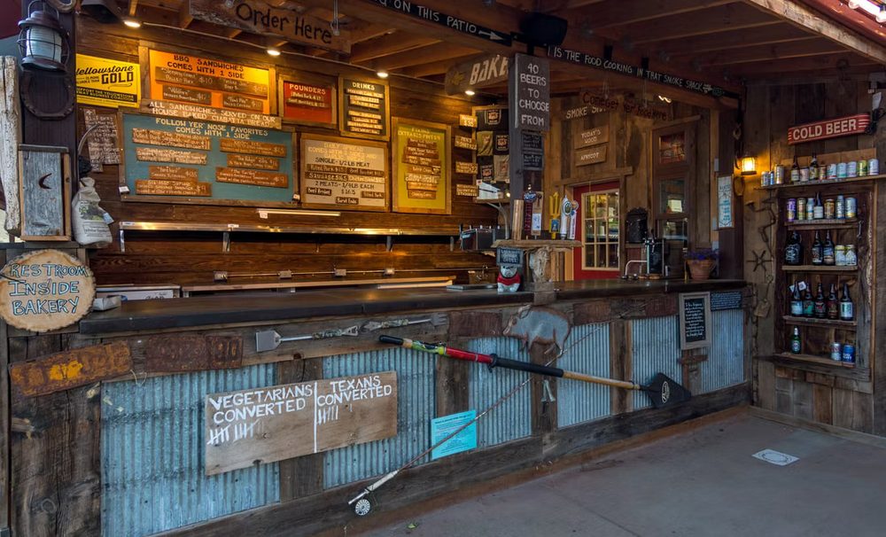 The order counter at Follow Yer' Nose BBQ: hand-lettered menu boards, a corrugated-metal bar and a shelf of craft beer
